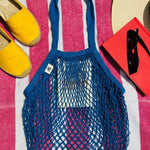 Blue bag laying on a towel outside